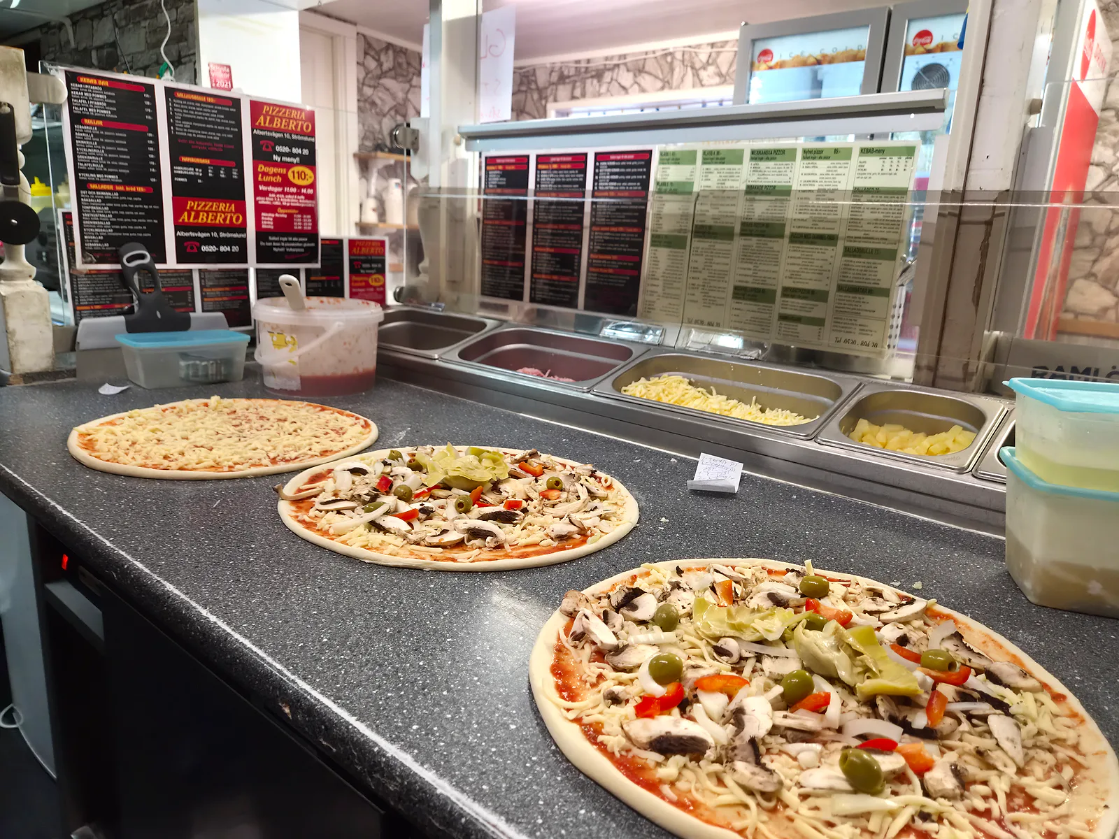 Pizzor på rad på bänken, redo för pålägg