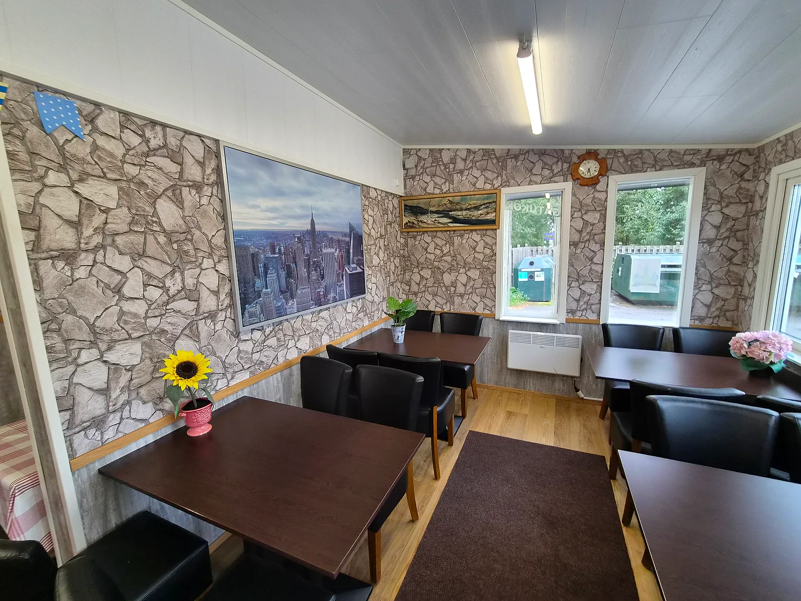Matsalen hos Pizzeria Alberto med bord vid fönstren och en solros på bordet