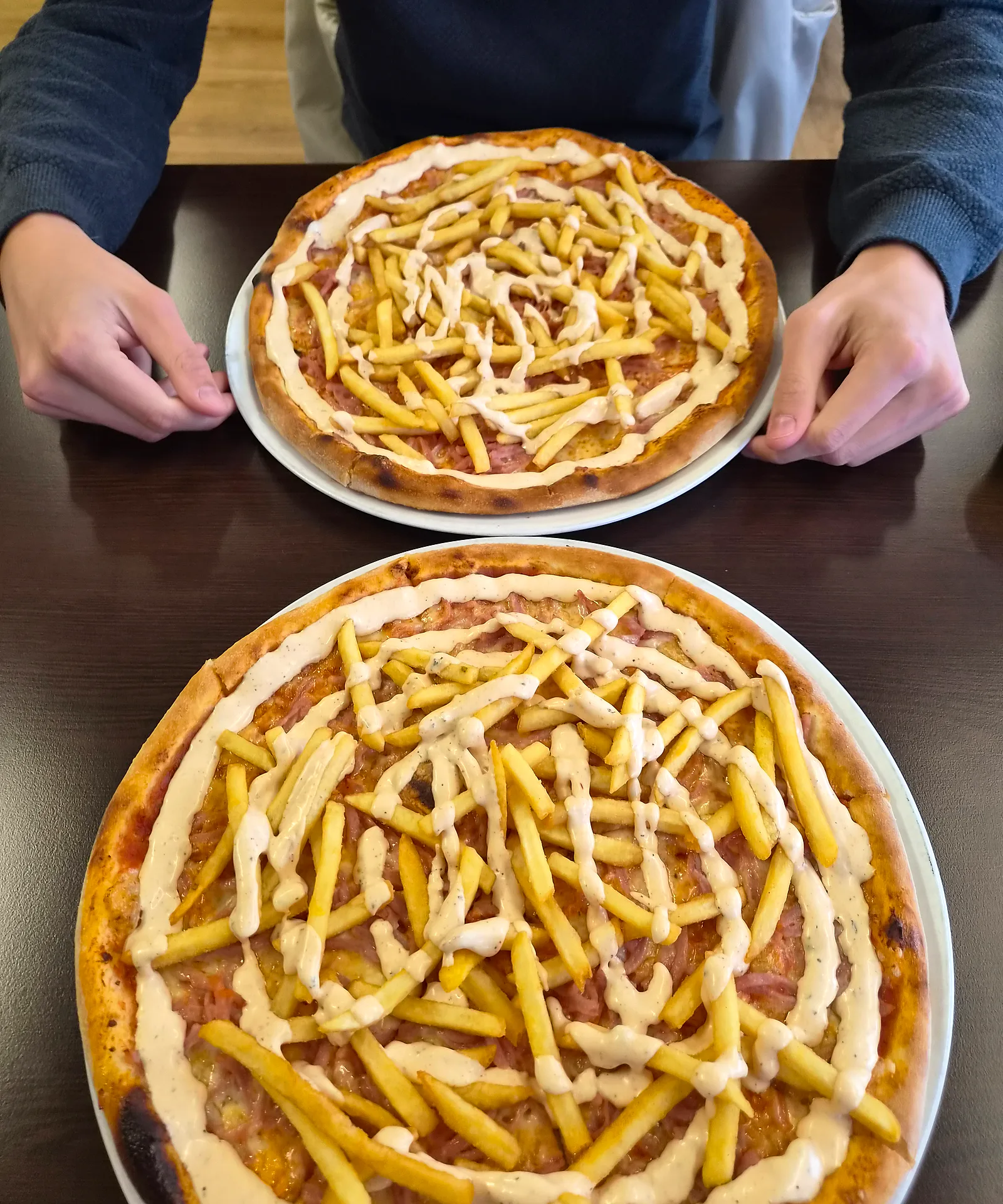 Pizzor med pommes och sås på ett bord i matsalen