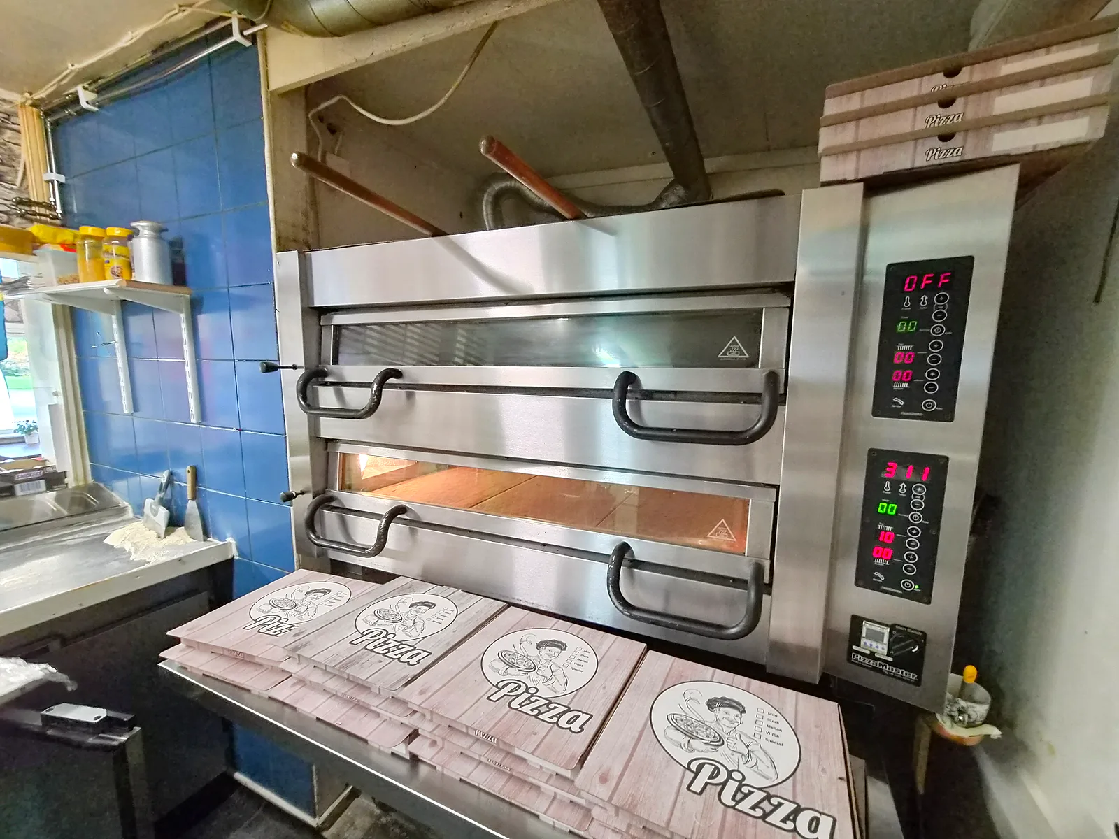 Pizzaugnen med staplade pizzakartonger framför